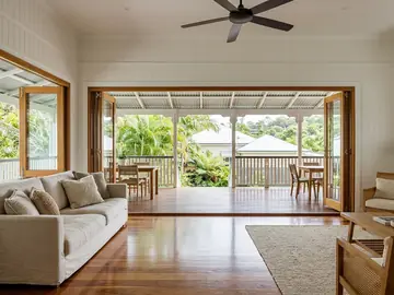 Living room opening through timber bi-fold doors onto a deep verandah